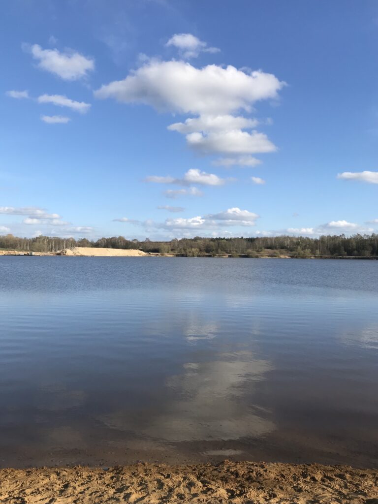 Blauer See mit Strand bei sonnigem Wetter